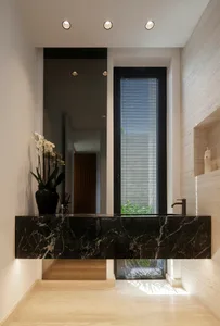 Modern bathroom with marble countertop and tall window with blinds.
