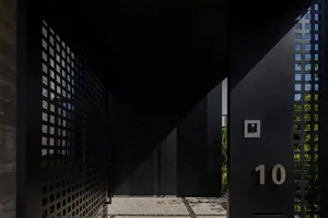 A modern, minimalist metal mesh gate with the number 10 on it and a view of a courtyard.
