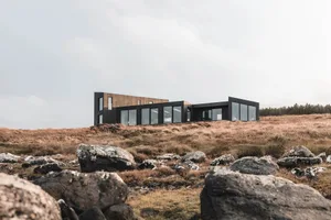 Modern metallic glass house with large windows and black exterior.