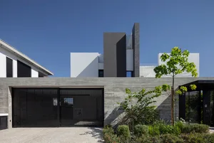 一座現代極簡住宅建築，搭配混凝土大門與俐落設計。