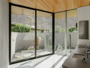 Modern minimalist bathroom with large glass door and wood ceiling.