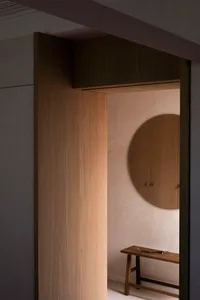 A minimalist interior with wooden accents and a wooden circular mirror.
