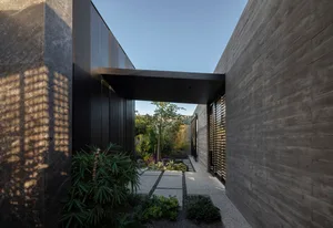 Modern entranceway with concrete walls and a metal walkway.
