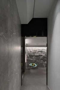 A modern corridor with concrete and marble walls and floor, featuring a green metallic chair in the background.