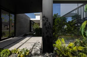 Concrete pathway with glass walls and lush greenery in the background.