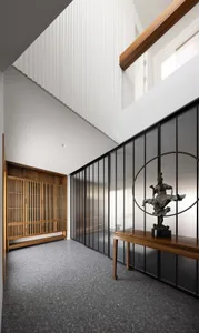 A modern interior entry hall with a wooden bench, glass walls, and a statue.