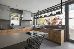 Modern kitchen featuring marble countertops, concrete walls, and glass shelves with various kitchenware.