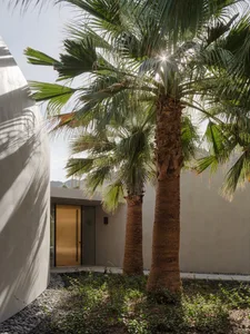 Modern minimalist residential entrance featuring concrete walls and large glass doors.