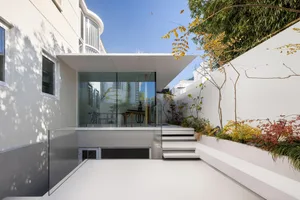 Modern, minimalist glass extension with white walls and outdoor space.