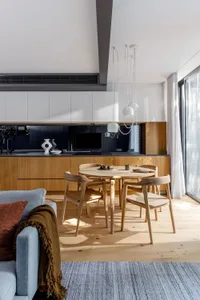 A modern residential kitchen with wood cabinets and a wooden dining table.