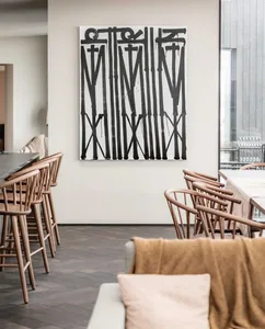 Modern restaurant interior with a bold black artwork on the wall and wooden furniture.