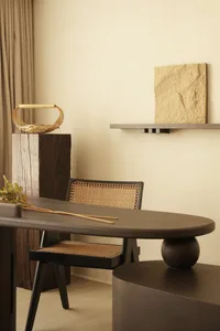 A modern dining space featuring wooden furniture with a woven basket on a wooden pedestal and a rock slab on a wall shelf.