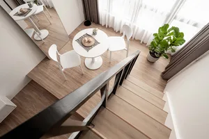 A minimalist dining area with white furniture, light wood flooring, and green plants.