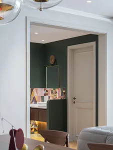 A modern bathroom with green walls, a wooden vanity, and colorful geometric tiles on the backsplash.
