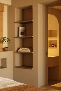 A minimalistic bedroom with a bed and built-in shelves.