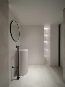 A minimalist bathroom with a modern concrete sink and white walls.
