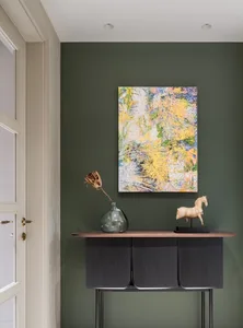 A modern console table with a black cabinet and a glass vase containing a dried flower.