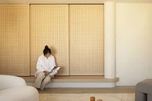 A modern interior living space featuring wooden walls and a woman reading a book