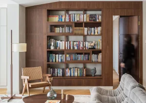 A modern library interior featuring wooden shelves filled with books and decorative items.