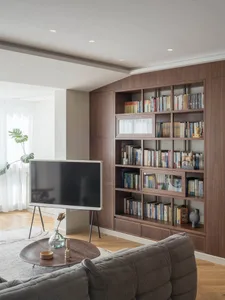 A modern living room featuring wooden shelves filled with books and decorative items.