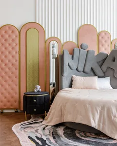 A bedroom with minimalist design, featuring a fabric headboard, wood flooring, and a carpet with abstract patterns.