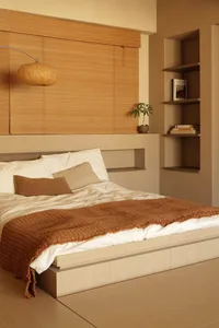 A minimalist bedroom with wooden bed platform, bamboo headboard, and fabric bedding and throw blanket.