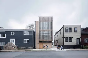 A modern residential building with brick, wood, and metal elements.