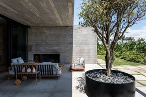 A modern patio with concrete elements, featuring a fireplace and seating area.