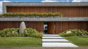 A modern entrance featuring a concrete walkway, a wooden facade, and a long wooden roof.