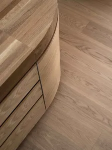 A modern interior design featuring a curved wooden case with a textured surface and minimalistic styling.