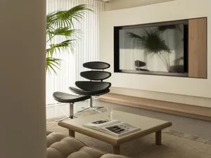 A modern living room with comfortable seating, a coffee table, a television, and a large window with a plant.
