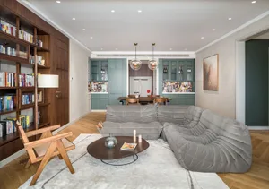 A modern living room featuring a grey sectional sofa, wooden coffee table, and a bookshelf filled with books.