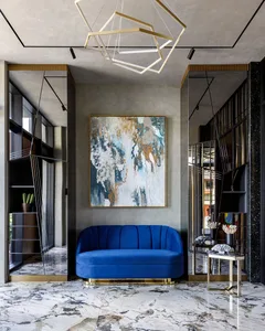 A modern living room with a blue velvet couch, a geometric chandelier, and a large abstract painting on the wall.