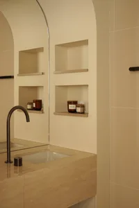 Modern bathroom interior with a marble countertop, built-in shelves, and a sleek faucet.