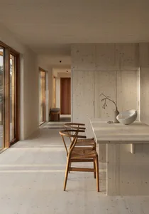 A modern minimalist kitchen featuring wooden finishes and a central island with a white bowl and vase.