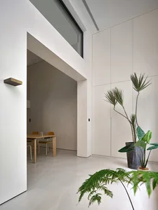 Modern minimalist living room with concrete walls, wood furniture, and large windows.