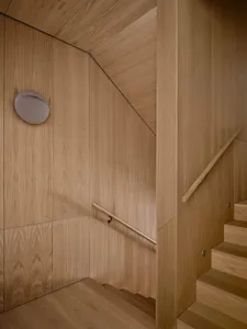 Modern minimalist staircase with wooden paneling and a circular light fixture.