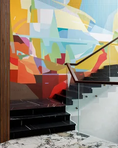 A modern staircase featuring artistic mural of geometric shapes and lines on a wall with glass and metal railings and marble 