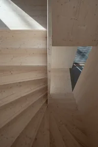 A modern, wooden staircase with a geometric design and natural light coming through a skylight.