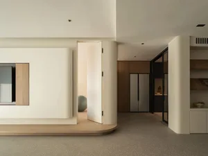 A modern living room with neutral-colored walls and flooring, featuring sleek furniture and minimalist design.
