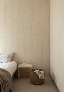 A minimalist bedroom featuring wooden walls and a wooden nightstand with a glass decanter and two glasses.