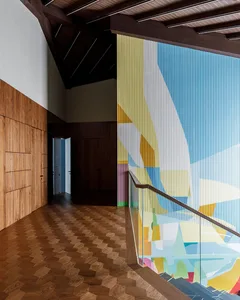 A modern corridor features a colorful abstract print wall and wooden flooring.
