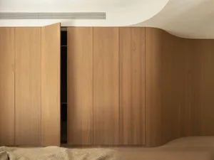 Modern minimalist bedroom featuring a curved oak wardrobe with an open door for storage
