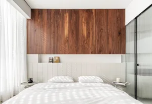 A modern minimalist bedroom featuring a wooden wall and white paneling.