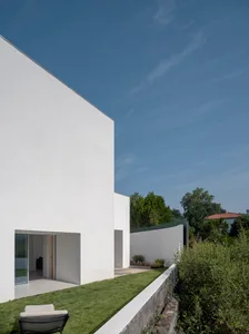 A minimalist, modern house with white stucco exterior walls and a bright blue sky.