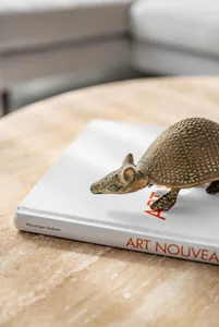 A metallic armadillo sculpture resting on a book titled "Art Nouveau"