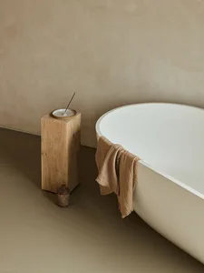 A minimalist bathroom with a porcelain bathtub and a wooden incense burner.