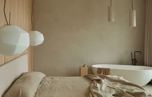 A minimalist bedroom featuring a textured wall and concrete floor, showcasing modern and serene design elements.