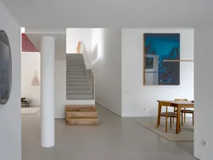 Modern minimalist interior design featuring concrete walls, stairs, and furniture in a contemporary setting.