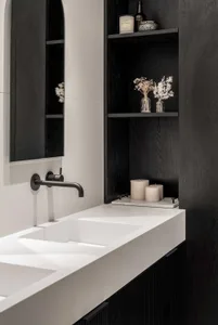 Modern bathroom with a sleek, minimalist design featuring a concrete counter and black shelving.